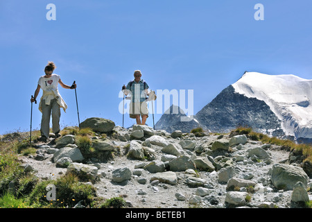 Due turisti / gli escursionisti a piedi lungo il sentiero di montagna in Svizzera Alpi Pennine / Walliser Alpen, Valais / Wallis, Svizzera Foto Stock