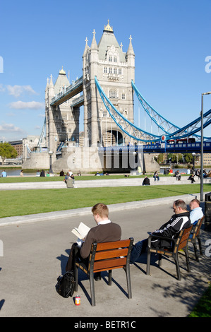 L'uomo della lettura in Potters Fields Park nella parte anteriore del Tower Bridge. Londra. La Gran Bretagna. Regno Unito Foto Stock