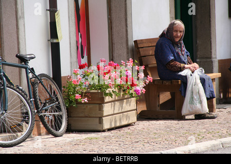 Vecchia signora seduta su una panchina in un villaggio italiano, Pesariis, Friuli Foto Stock