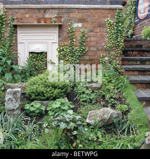 Moss-coperta di pietre e piccole conifere con piante verdi su rockery in città giardino Foto Stock