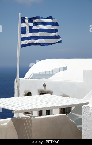 Bandiera Greca battenti nel vento al di sopra di una proprietà bianco Oia - Santorini, Grecia Foto Stock