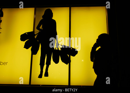 Gli amanti dello shopping a piedi passato un annuncio su un negozio di fronte a Oxford Street a Londra il Boxing Day. Foto Stock