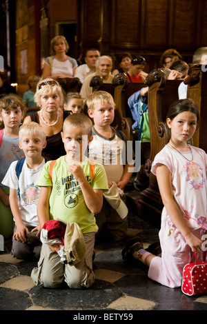 Bambini polacchi in una scuola di partito pregare nella navata della chiesa di St Marys Basilica. Cracovia. La Polonia. Foto Stock