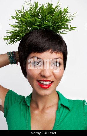 Bella donna tenendo un impianto dietro la testa Foto Stock