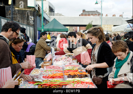 Persone che acquistano caramelle a Brick Lane market stallo. Londra. La Gran Bretagna. Regno Unito Foto Stock