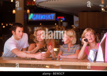 Tre donne svedesi in seduta marciapiede coffee house parlando su telefoni cellulari Foto Stock