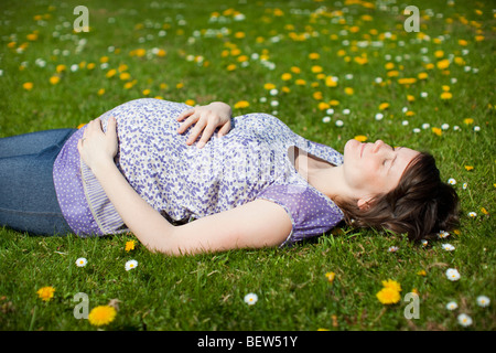 Donna incinta sdraiati sull'erba Foto Stock