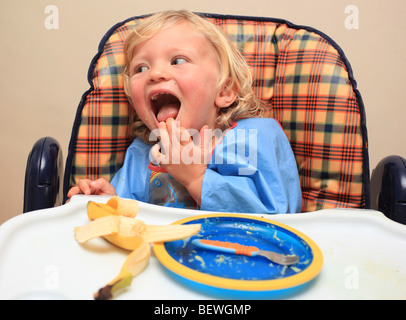 Bambino in un seggiolone avente il pranzo Foto Stock