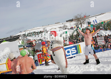 Frequentatori di partito giocare nella neve, vestito in costume da lungo con mascotte Bonhomme durante l'inverno Carnaval in Quebec Foto Stock