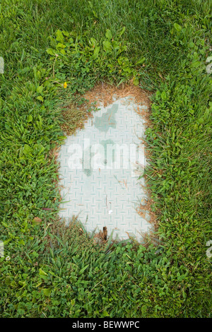 Valvola acqua piastra ricoperta da erba nel parco pubblico, Nuovo Messico, STATI UNITI D'AMERICA Foto Stock