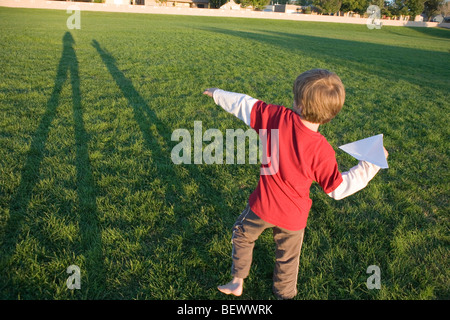 Sette anni di vecchio ragazzo sempre pronto a lanciare il suo aeroplano di carta in un parco Foto Stock