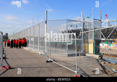 La scuola dei bambini visitando il perimetro del London 2012 Giochi Olimpici sito con stadio principale al di là Foto Stock