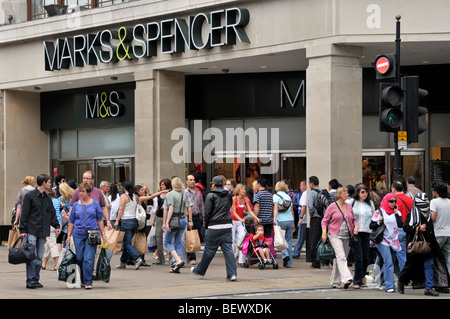 La trafficata Oxford Street shopping folla di acquirenti e turisti che camminano sul marciapiede Marks e Spencer Marble Arch, il negozio di affari di fronte Londra UK Foto Stock