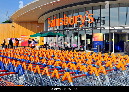 Sainsburys, supermercato, insegna e negozio, parcheggio carrello e ingresso al negozio con caffetteria Starbucks, Greenwich, Londra, Inghilterra, Regno Unito Foto Stock