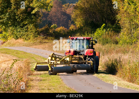 Agricoltore in caso II 155 il trattore e il rullo guidato lungo il vicolo del paese - sud-Touraine, Francia. Foto Stock