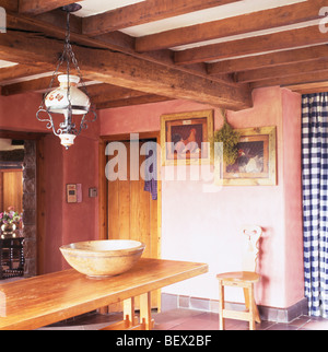 Vittoriano lampada in vetro sopra la tabella di pino in rosa cottage sala da pranzo in stile rustico con travi a vista sul soffitto Foto Stock