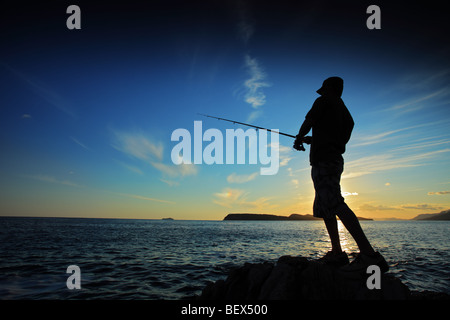 Uomo di pesca sul tramonto Foto Stock