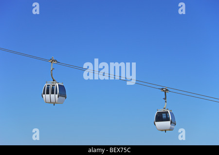 Due aria cabine cavo contro un cielo blu a Lisbona, Portogallo Foto Stock