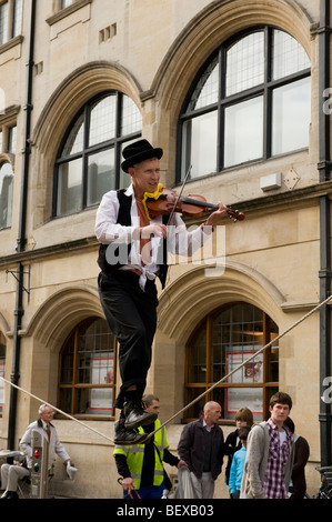 Street animatore, un funambolo in Oxford, Regno Unito la riproduzione di un violino per denaro Foto Stock
