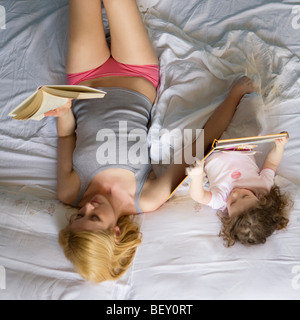 Madre e figlia giacente sul letto, la lettura Foto Stock