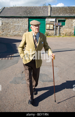 Il vecchio uomo a camminare con un bastone e il tappo piatto. Northumberland nell Inghilterra del Nord Foto Stock