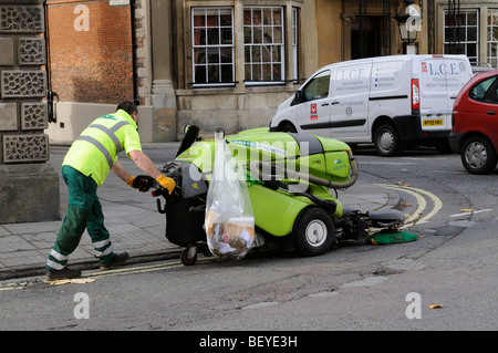 Opera utilizzando un camminare dietro di pavimentazione e spazzatrice stradale sul marciapiede in Devizes town center Wiltshire, Inghilterra REGNO UNITO Foto Stock