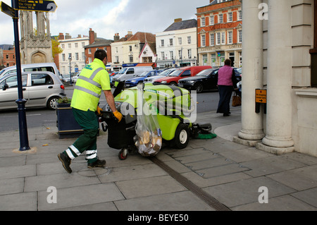 Opera utilizzando un camminare dietro di pavimentazione e spazzatrice stradale sul marciapiede in Devizes town center Wiltshire, Inghilterra REGNO UNITO Foto Stock