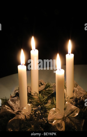 Natale corona di Avvento con candele accese poste sul tavolo con sfondo nero Foto Stock