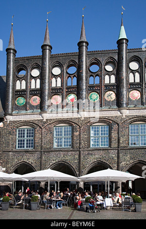 La gente seduta a mangiare presso il cafe bar in piazza del mercato al di fuori del Municipio di Lubecca Germania Foto Stock