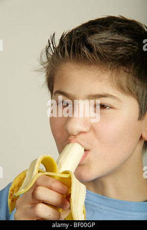 Ritratto di un giovane ragazzo di mangiare una banana Foto Stock