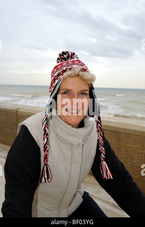 Donna di mezza età godendo in bicicletta indossando cappellino lungo Undercliff a piedi vicino a Brighton Foto Stock