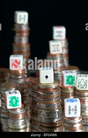 Studio shot di pile di monete con il poker di dadi sulla parte superiore di pile con sfondo nero Foto Stock