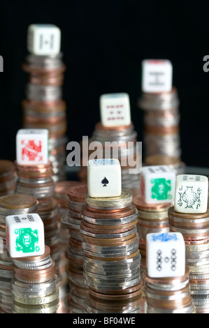 Studio shot di pile di monete con il poker di dadi sulla parte superiore di pile con sfondo nero Foto Stock