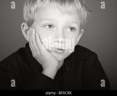 Inquadratura di un ragazzo biondo cercando premuto Foto Stock