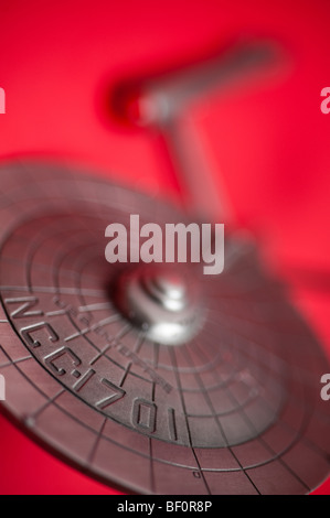 Un modello di peltro del famoso Starship USS Enterprise, da TV Star Trek, visualizzato su uno sfondo di colore rosso. Foto Stock