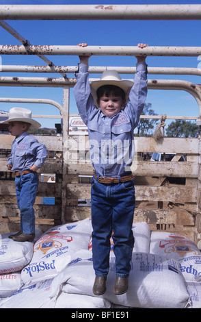 Due ragazzi, bambini, cowboy in abbinamento Stetson cappelli, magliette e jeans, giocare nel retro del carrello durante il rodeo, Queensland Australia Foto Stock