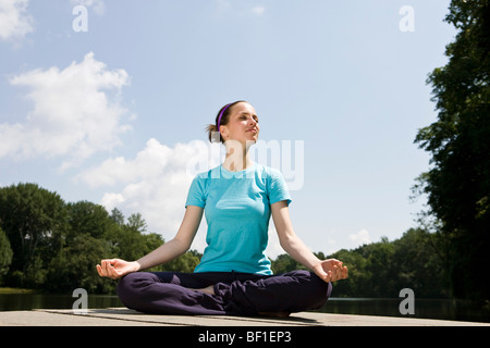 Una giovane donna a praticare yoga in banchina Foto Stock