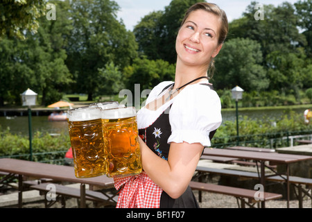 Tradizionalmente un vestito donna tedesca che serve birra in un giardino della birra Foto Stock