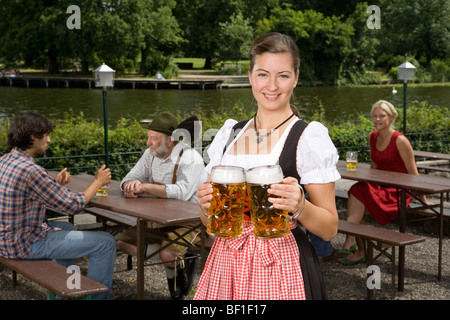 Tradizionalmente un vestito donna tedesca che serve birra in un giardino della birra Foto Stock