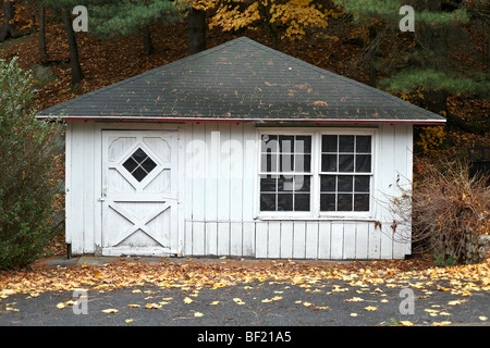 Graziosa dependance con dipinti di bianco verticale schierandosi in legno & pannellata diamond vetrata porta in legno nel paesaggio autunnale Foto Stock