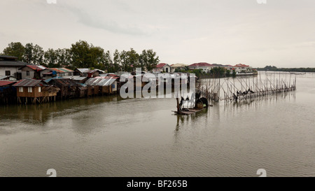 Shanty case su palafitte accanto al pesce di bambù trappole in un fiume. Iloilo philippines Foto Stock