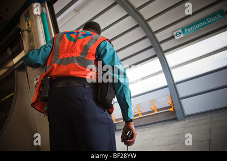 Un Docklands Light Railway conduttore tenendo un walkie-talkie attende di chiudere le porte a Pontoon Dock Station, East London Foto Stock