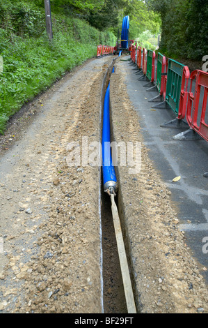 Acqua principali essendo prevista trincea scavata dalla macchina di scavo in Hampshire Inghilterra Foto Stock