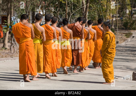 Buddhistic monaci a camminare su una strada di fronte al monastero di Iva Phonphao Pa, Luang Prabang, Laos Foto Stock