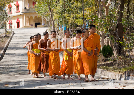 Buddhistic monaci a camminare su una strada di fronte al monastero di Iva Phonphao Pa, Luang Prabang, Laos Foto Stock