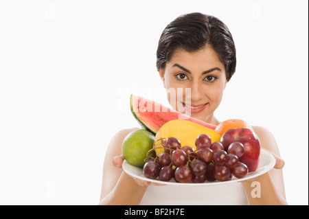 Ritratto di una donna tenendo un piatto di frutti assortiti Foto Stock