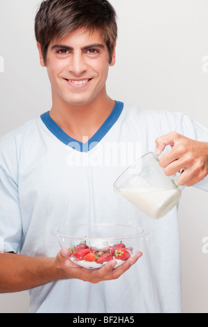 Ritratto di un uomo versando il latte sulle fragole Foto Stock
