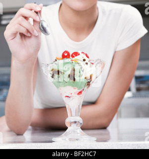 Ragazza adolescente di mangiare un gelato in una gelateria Foto Stock