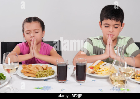 Ragazzo e sua sorella pregare prima di pranzo Foto Stock