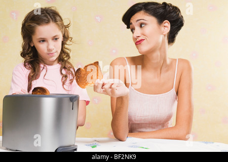 Donna che sua figlia un pezzo di toast bruciato Foto Stock